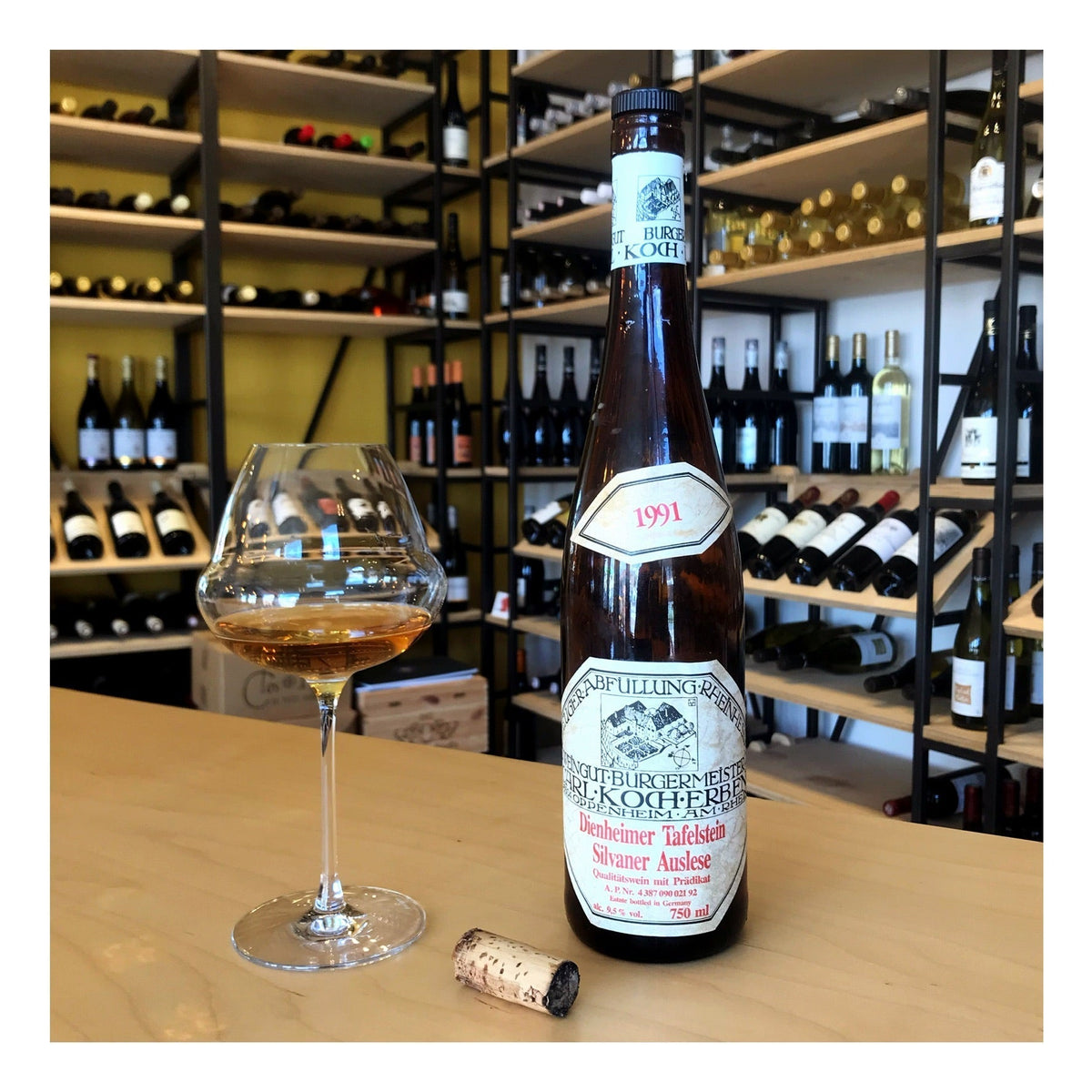 Fles silvaner auslese uit 1991 van Carl Koch. Naast de fles staat een ingeschonken Lehmann Oenomust glas. De wijn heeft een diepe barnsteen kleur. De kurk ligt tevens op tafel en is in goede conditie, maar heeft een zeer zwarte bovenkant.